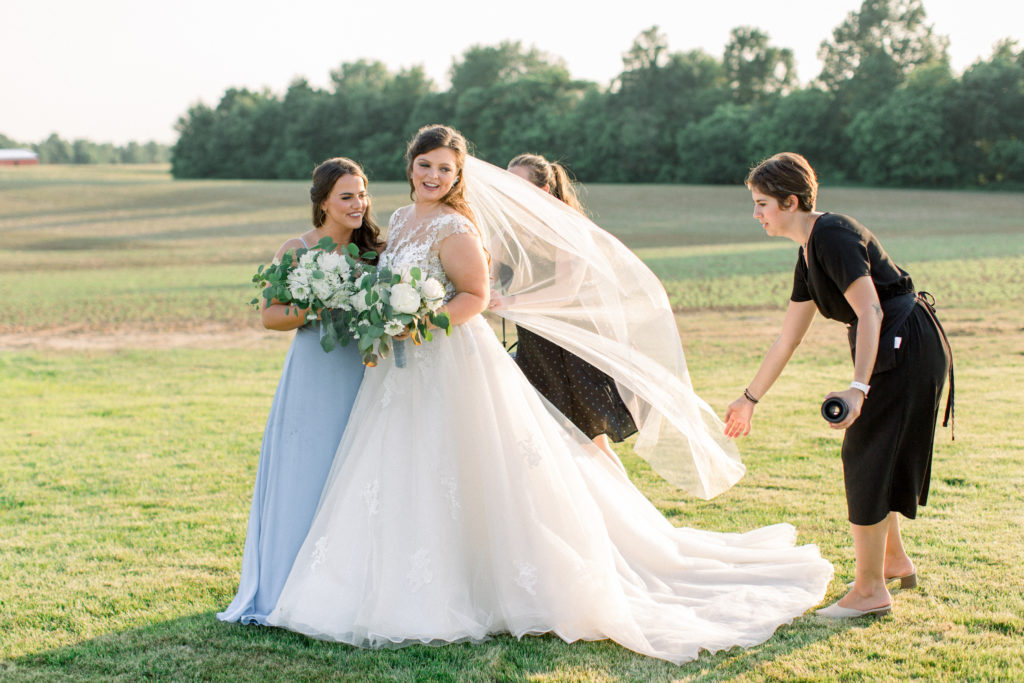 Our team members Cori and Becca helping our bride with her veil at a wedding in Madisonville, Kentucky